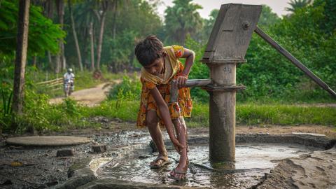 Rural Girl Using Hand Pump for Water
